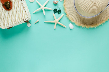 Tropic flat lay with straw hat, bag, starfish, shells, sunglasses, boat, earrings on green background. Summer fashion flat lay, vacation, travel concept. Top view with copy space. 