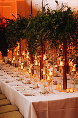 Wall Mural - Hindu wedding reception dinner. Tables served with greenery, shiny candles and rose gold decor stands in the restaurant