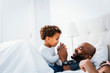 © Cavan Images - Happy father playing with son while relaxing on bed against wall at home