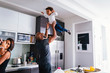© Cavan Images - Smiling parents playing with children in kitchen at home