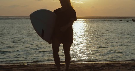 Wall Mural - Silhouette of beautiful surfer girl on beach at sunset