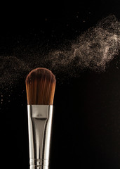 Wall Mural - Close up powder splash and brush for makeup artist or beauty blogger in black background