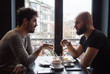 Two young guys with beards drink a coffee and having a nice conversation.