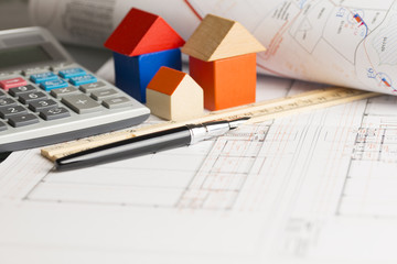 New house plan or project, with ruler, pen and miniature house from wooden blocks 