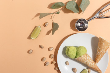 Wall Mural - Pistachio ice cream balls in waffle cones on a plate on a beige background. Top view.