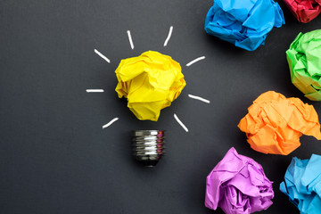 Great idea concept with crumpled colorful paper and light bulb on black background