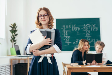 Portrait of smiling school girl with books in classroom