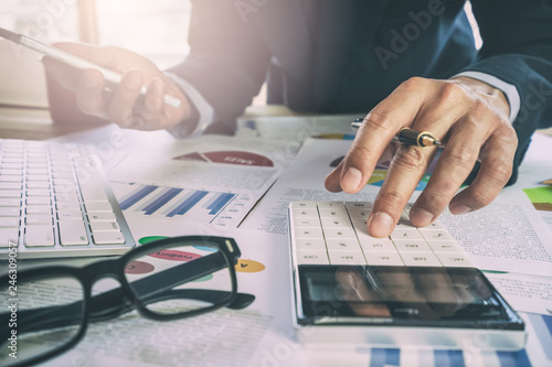 Fotomural Businessman or accountant working on calculator to calculate business data concept