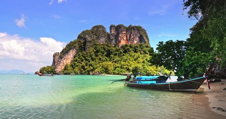 Wall Mural - Sea coast of Thailand island. Clean water and sandy beach with traditional wooden longtail boat on shore waiting for tourists and travelers