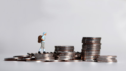 Canvas Print - A miniature young woman walking on a pile of coins.