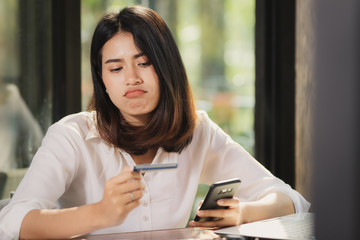 Asia woman using smartphone and holding card with worried.