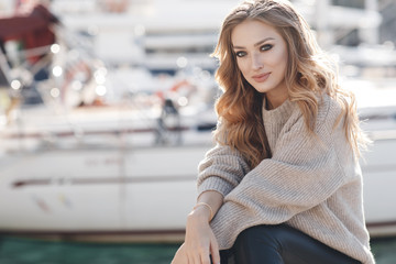 Portrait of beautiful woman with long curly blond hair outdoors in spring. Young woman with natural makeup in a gray jacket . A smart photo of a young beautiful woman in autumn clothes.