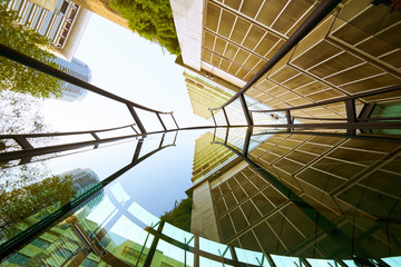 Wall Mural - Low angle shot of modern glass buildings and green with clear sky background.