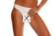 © vladimirfloyd - Woman with panties cowers her vagina with X sign drawn on sheet of paper on white background