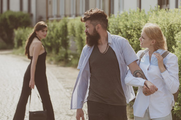 Wall Mural - A bad boy. Love triangle and threesome. Bearded man looking at other girl. Man cheating his wife or girlfriend. Hipster choosing between two women. Betrayal and infidelity. Unfaithful love