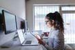 © Dusan Petkovic - Side view of hard working Caucasian female architect using tablet for work while sitting in the office. In front of her on desk laptop. White color dominating.