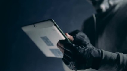 Hacker uses a tablet while cracking system, close up.