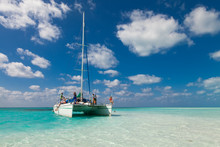 Group Of Unidentified Tourists Travel On A Catamaran Near The Island Of Kayo Largo.  White Catamaran On A Background Of Blue Sky And Azure Water