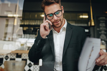 entrepreneur talking on cell phone looking at office papers in a