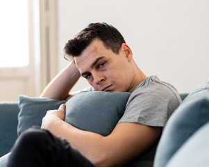 Wall Mural - Young man suffering from depression lying on sofa alone at home feeling frustrated and hopeless