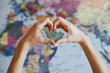 © zakalinka - female hands in form of heart against world map background