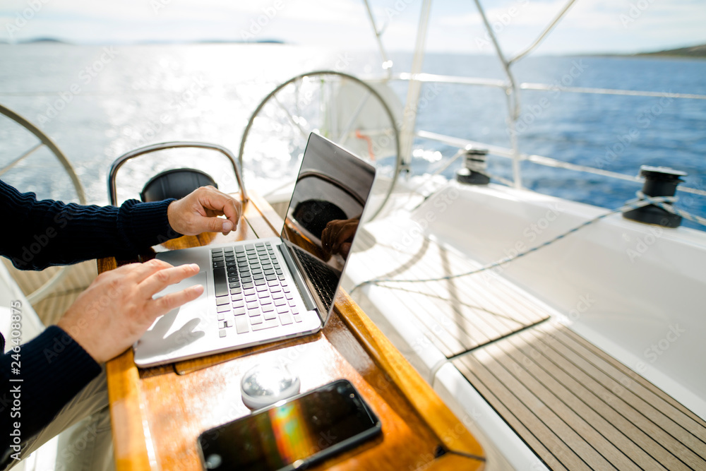 Digitaler Nomade mit Laptop arbeitet auf einem Segelboot - obrazy, fototapety, plakaty 