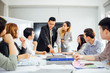© Yingyaipumi - Businesswoman presenting to colleagues at a meeting.Successful team leader and business owner leading informal in-house business meeting. Businessman working on laptop in foreground.