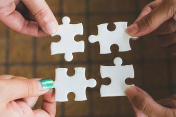 Hands of diverse people assembling jigsaw puzzle, team put pieces together searching for right match, help support in teamwork to find common solution concept, top close up view