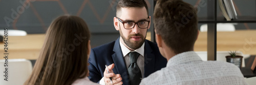 Rear back view couple meets with realtor real estate agent in office, consulting Tableau sur Toile