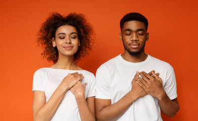 Kind woman and man keep both palms on chest