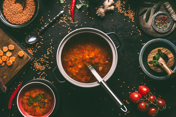 Wall Mural - Healthy vegan lentil soup in cooking pot with ladle on dark kitchen table background with ingredients. Vegetarian food. Clean diet eating. Source of plant based protein