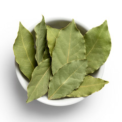 Wall Mural - Dried bay leaves in white ceramic bowl isolated on white from above.