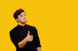 attractive and satisfied man, showing positive gesture with his thumb, satisfied human emotion, isolated on yellow background