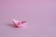 light pink paper boat on a light pink background. A lonely woman who lives alone. A feeling of depression and despair. A symbol of independence and courage on the road that a woman creates for herself