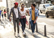 © BalanceFormCreative - Group of friends hangout at the city street.Female sitting on skate board while friends pushing her from behind.