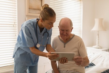 Wall Mural - Female doctor and senior man using digital tablet