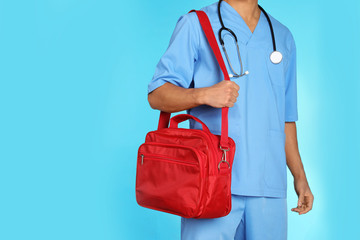 Wall Mural - Male doctor with first aid kit and space for text on color background, closeup. Medical object