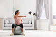 © New Africa - Young woman doing exercise with dumbbells on fitness ball at home. Space for text