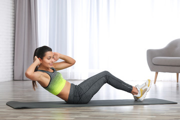 Sticker - Young woman in fitness clothes doing exercise at home. Space for text