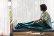 © ronnarong - Lonely elderly female patient sitting on bed at hospital and looking away outside the window waiting to see her family to visit.