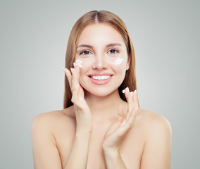 Young woman applying cream on healthy skin, spa portrait