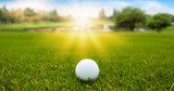 Golf ball on green grass on blurred beautiful landscape of golf course with sunrise,sunset time on background. 