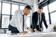 © LIGHTFIELD STUDIOS - businessmen having discussion while standing near desk in modern office