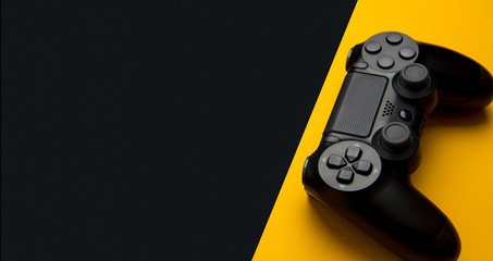 Wall Mural - black wireless gamepad on a black and yellow background