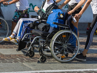 Wall Mural - Disabled Athlete in a Sport Wheelchair during Marathon Helped by Female Runners