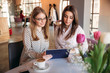 © Aleksandr - Two girls use a tablet while sitting in a cafe and drinking coffee. Business woman