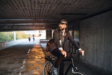 Hipster businessman commuter with electric bicycle traveling to work in city.