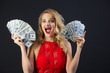 © Alexandr - beautiful young girl with hairstyle and makeup in a red dress holding dollars in her hands