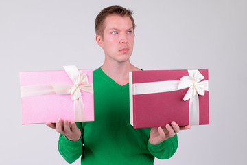 Young handsome man thinking with two gift boxes for Valentine's day