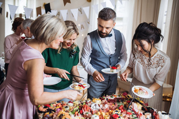 Wall Mural - Multigeneration family putting food on plates on a indoor family birthday party.